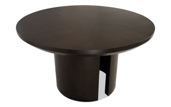 Round dark brown wooden dining table with a smooth finish and a cylindrical base featuring a vertical cutout, modern design.