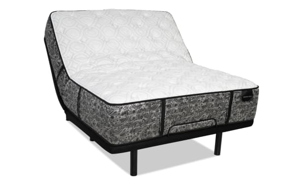 Adjustable bed base with a white quilted mattress featuring a gray paisley pattern, black trim, and the label "DISTINCTION" visible.