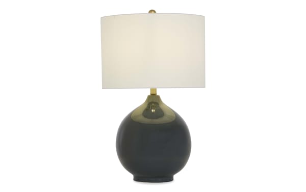 Table lamp with a glossy black ceramic round base, brass accents, and a white fabric drum shade, suitable for modern decor.