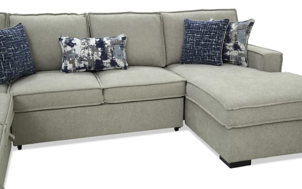 Light gray fabric sectional sofa with chaise lounge, featuring plush cushions and decorative blue and gray patterned throw pillows, modern design.