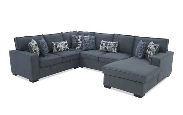 Dark blue fabric sectional sofa with chaise, featuring multiple patterned throw pillows and modern block legs, suitable for living room seating.