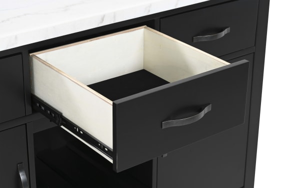 Black wooden kitchen cabinet drawer with metal handle, fully extended to show light wood interior and metal sliding rails, under white marble countertop.