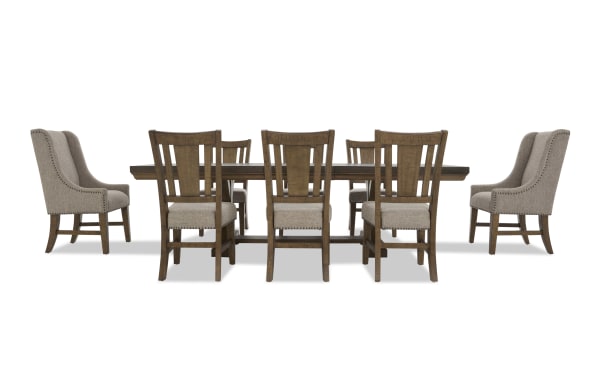 Dining room set with a dark wood rectangular table and eight chairs, featuring beige upholstered seats and backs with nailhead trim.