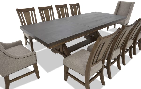 Rustic wooden dining table set with a dark wood rectangular table and ten chairs, featuring beige upholstered seats and nailhead trim accents.