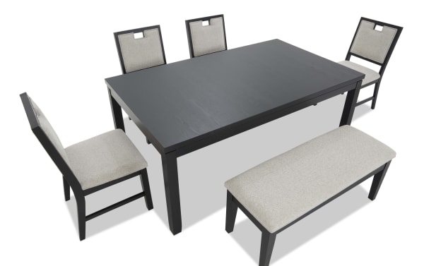 Black wooden dining table set with four beige cushioned chairs and a matching bench, featuring modern design and fabric upholstery.