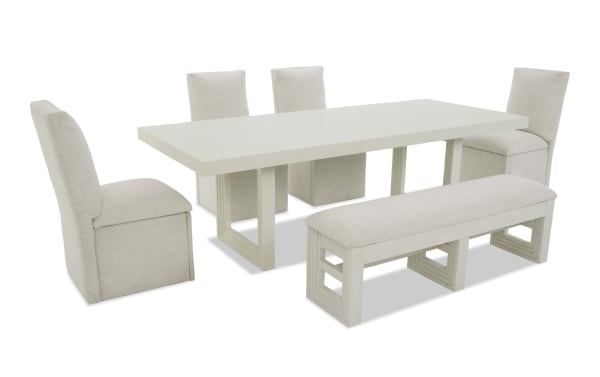 Modern white dining table set with six beige upholstered chairs and a matching bench, featuring a sleek rectangular tabletop and geometric wooden legs.