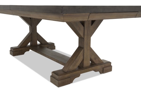 Rustic brown wooden trestle table base with sturdy X-shaped supports and a thick connecting beam, showcasing a distressed finish.