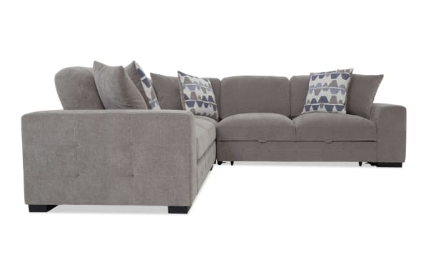 Gray fabric sectional sofa with tufted sides, plush cushions, and patterned throw pillows, ideal for modern living rooms.