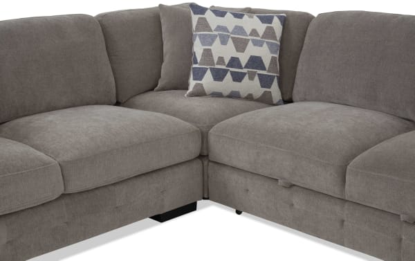 Sectional sofa with soft gray fabric upholstery, featuring plush cushions and a geometric patterned throw pillow, ideal for modern living rooms.