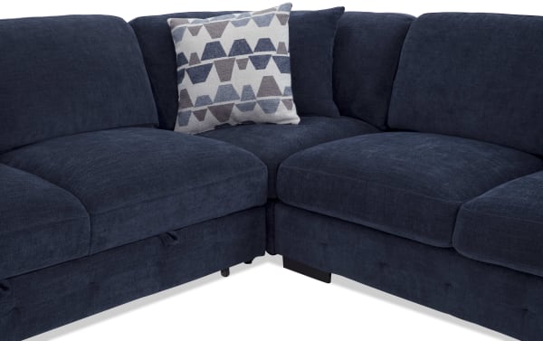 Dark blue fabric sectional sofa with plush cushions and a patterned gray and blue throw pillow, showcasing modern comfort and style.