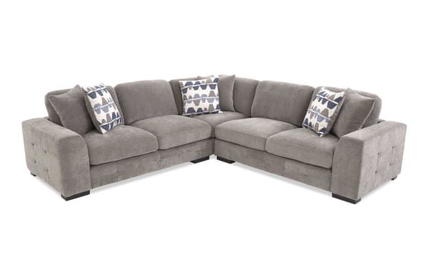 Gray fabric sectional sofa with tufted armrests, plush cushions, and three patterned blue and white throw pillows, ideal for modern living rooms.