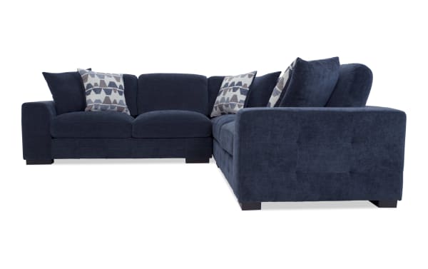 Modern navy blue sectional sofa with plush fabric upholstery, L-shaped design, cushioned seats, and geometric patterned throw pillows for living room seating.