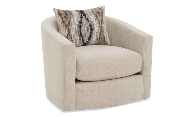 Beige fabric swivel barrel chair with textured upholstery, curved arms, and a decorative brown and black patterned accent pillow.