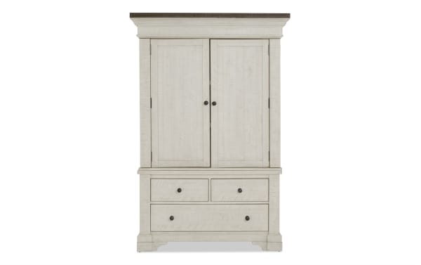 Whitewashed wooden armoire with two doors, two small drawers, and one large drawer, featuring black round knobs and a classic design.