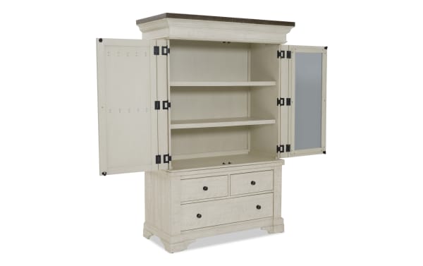 White wooden storage cabinet with open double doors, two interior shelves, and three drawers with black knobs, featuring a dark wood top.