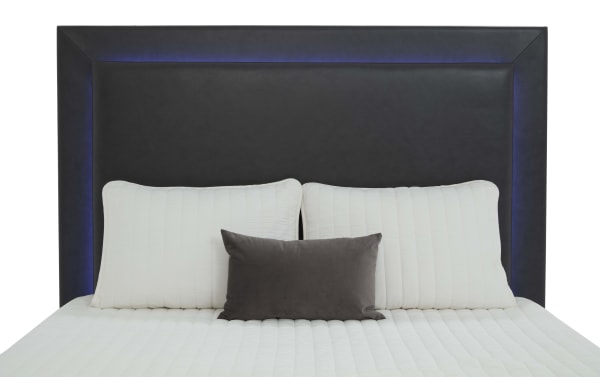 Black leather upholstered headboard with subtle blue LED backlighting, paired with white quilted pillows and bedding, showcasing modern bedroom decor.