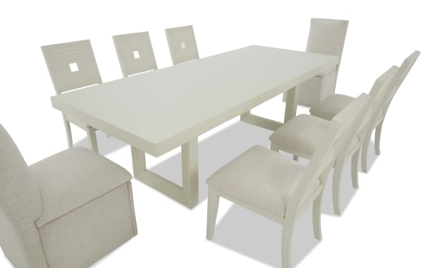 Modern rectangular white dining table with eight beige upholstered chairs, featuring wooden frames and cushioned seats, suitable for contemporary dining rooms.