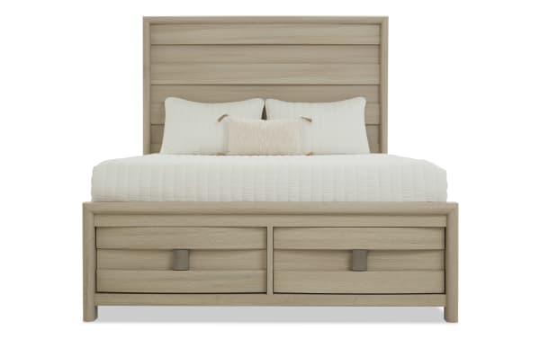 King-size wooden bed frame with light oak finish, featuring a paneled headboard and two front storage drawers, styled with white bedding and pillows.