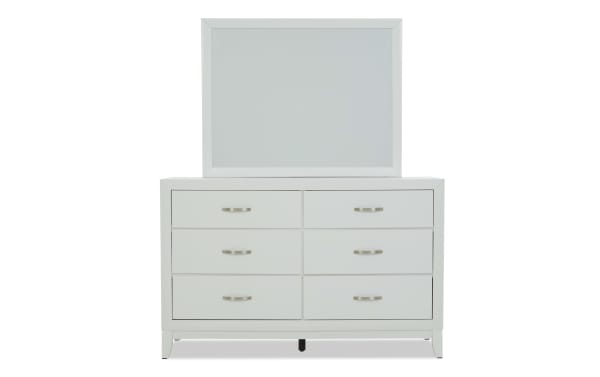 White wooden dresser with six drawers and silver handles, topped with a large rectangular mirror, modern minimalist bedroom furniture.
