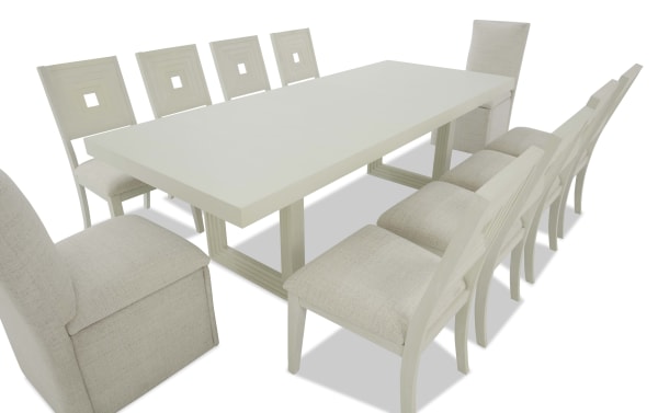 Modern rectangular white wooden dining table set with ten beige upholstered chairs featuring square cut-out backrests, ideal for large dining spaces.