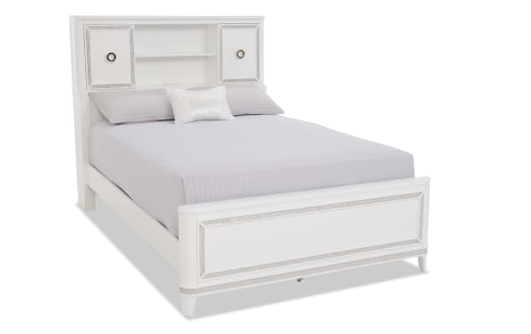White wooden bed frame with built-in headboard shelving and storage cabinets, decorative trim, and light gray bedding, modern style