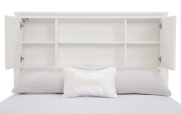 White wooden bed headboard with built-in open shelving and two cabinet doors, shown with light gray pillows and bedding.