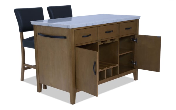Wooden kitchen island with white marble countertop, three drawers, double-door cabinet with wine rack, and two black cushioned bar stools.