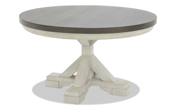 Round farmhouse dining table with a dark wood top and white distressed pedestal base, featuring sturdy crossbeam support.