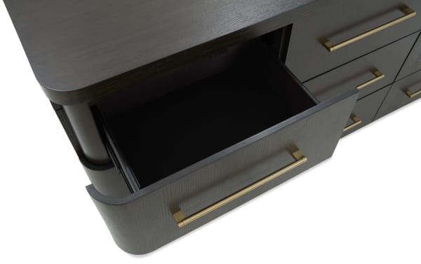 Dark wood dresser drawer with a gold metal handle partially open, showcasing smooth black interior and rounded corner design.