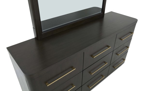 Dark wood dresser with a smooth finish, featuring nine drawers with long brass handles and a matching framed mirror on top.