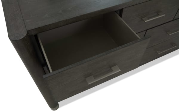 Dark wood dresser drawer partially open, showing smooth metal handle and clean interior, highlighting modern bedroom storage furniture.