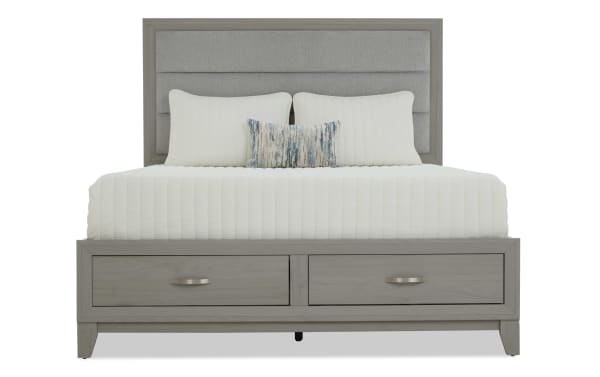 Gray wooden bed frame with a padded headboard and two under-bed storage drawers, styled with white bedding and decorative pillows.
