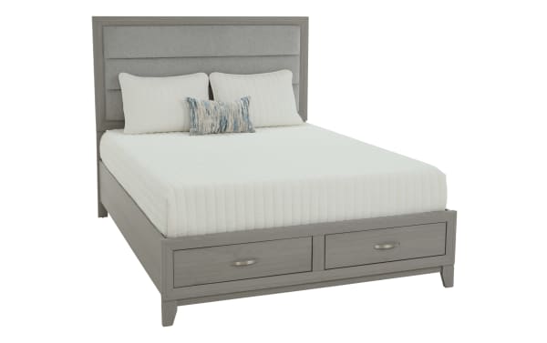 Queen-size bed with light gray wooden frame, upholstered padded headboard, white quilted bedding, two white pillows, one decorative pillow, and two storage drawers at the foot.