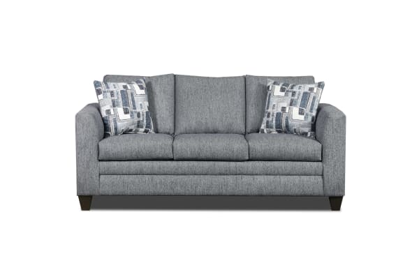 Gray fabric three-seater sofa with dark wooden legs and two patterned blue and white throw pillows, modern living room furniture.
