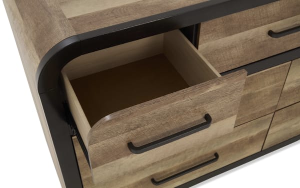 Wooden drawer with black metal handle, partially open, showing smooth interior and rounded edges, part of rustic-style dresser.