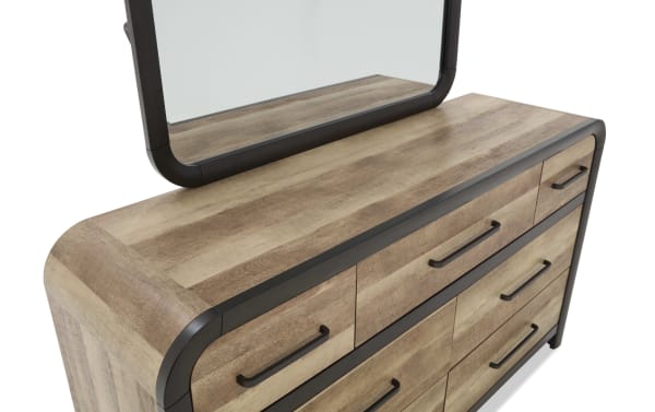 Wooden dresser with a light brown finish, black metal handles, rounded edges, and an attached rectangular mirror with a black frame.