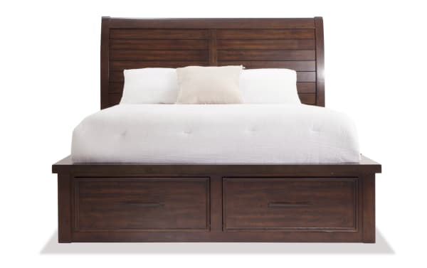Dark wood sleigh bed with horizontal slat headboard, white bedding, beige accent pillow, and built-in storage drawers at the base.