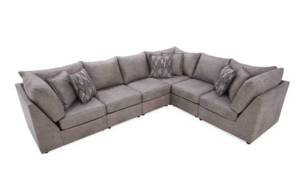 Gray fabric L-shaped sectional sofa with plush cushions and patterned throw pillows, modern design for living room seating.