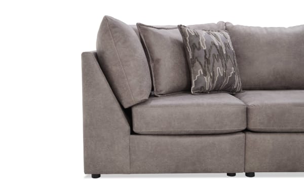 Modern sectional sofa in taupe microfiber fabric with plush cushions and a decorative patterned throw pillow, showcasing contemporary living room furniture design.