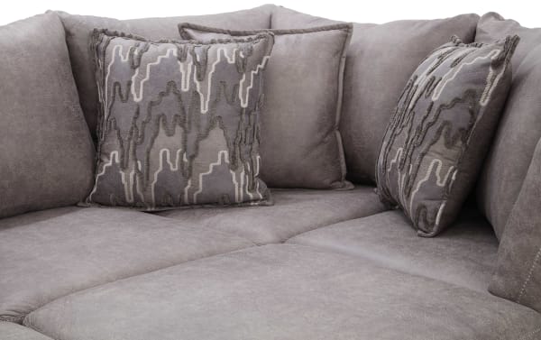 Gray sectional sofa corner with soft microfiber upholstery and decorative patterned throw pillows, highlighting modern living room comfort and style.