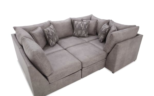 Gray sectional sofa with plush cushions and patterned throw pillows, featuring a modern design and soft fabric upholstery for living room seating.
