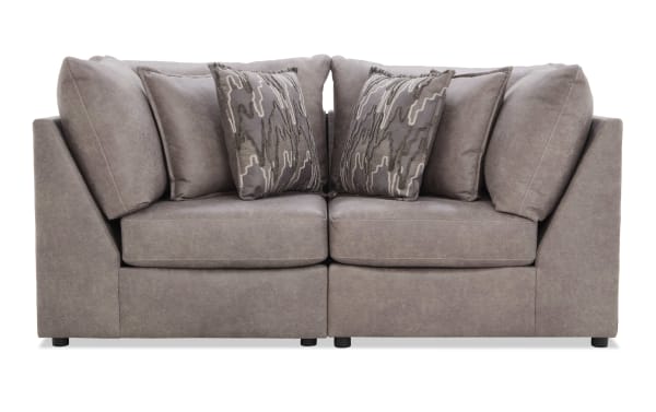 Modern gray fabric sectional sofa with plush cushions and patterned throw pillows, featuring a sleek, contemporary design ideal for living rooms.