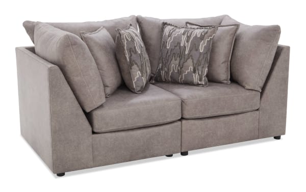 Modern gray fabric sectional sofa with plush cushions and patterned throw pillows, featuring a sleek, angled arm design and low black legs.