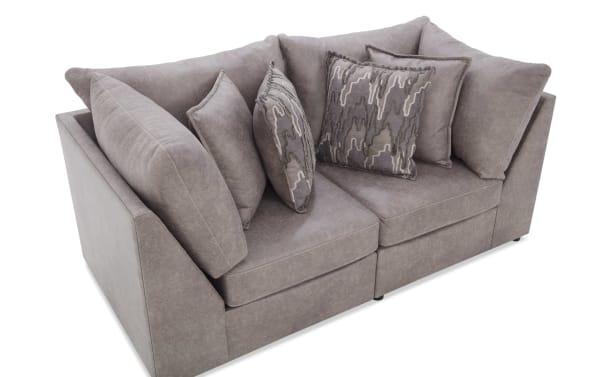 Modern gray fabric corner sofa with plush cushions and patterned throw pillows, designed for comfortable living room seating.