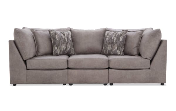 Modern gray fabric sofa with plush cushions and patterned accent pillows, featuring a clean, boxy design and low black legs.