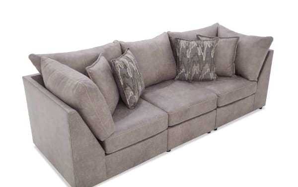 Modern sectional sofa in muted taupe fabric with plush cushions and patterned accent pillows, ideal for contemporary living rooms.