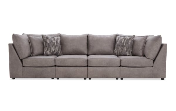 Modern sectional sofa upholstered in soft gray fabric with plush cushions and patterned accent pillows, designed for spacious living rooms.