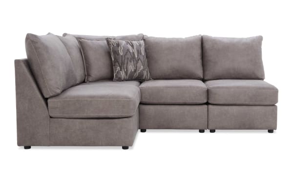 Sectional sofa in soft gray fabric with plush cushions and a patterned accent pillow, featuring a modern L-shaped design for living room seating.