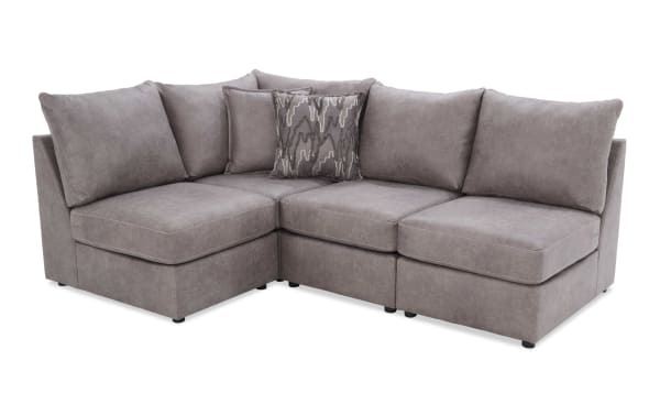 Modern sectional sofa with soft gray fabric upholstery, plush cushions, and a patterned accent pillow, ideal for living room seating.