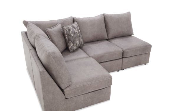 Gray sectional sofa with plush cushions and a patterned accent pillow, featuring soft fabric upholstery and modern design.